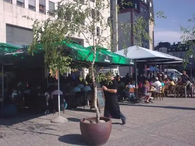 a man walking down a street with a tree in a pot at Apartma N'Poznam župa in Ljubljana
