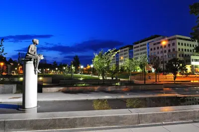 a statue of a man sitting on a pedestal at night at Apartma N'Poznam župa in Ljubljana