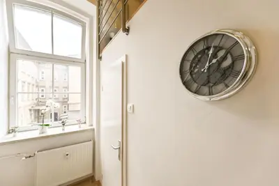 a clock on the wall in a room with a window at Apartma N'Poznam Tobačna 2 in Ljubljana