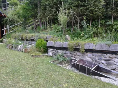 a stone wall with a bench in a garden at Holiday Home Prdelanca in Luče