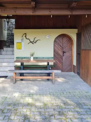a wooden bench sitting in front of a building with a door at Idyllisches Haus in der Natur in Šoštanj