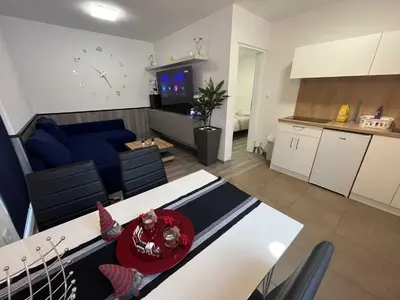 a living room and kitchen with a child sitting on a table at Apartment Adam & Eva, Near terme Olimia, Free Parking in Podčetrtek