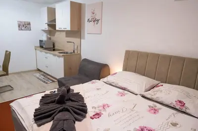 a bedroom with a bed and a chair and a kitchen at Apartmaji Irma in Moravske Toplice