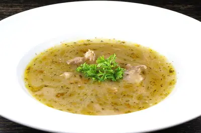 a white bowl of chicken soup with a garnishment at Gostisce Sobocan in Maribor