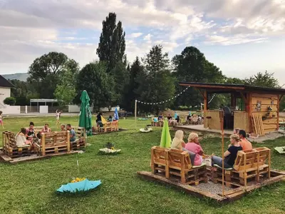 a group of people sitting on benches in the grass at Gostisce Sobocan in Maribor
