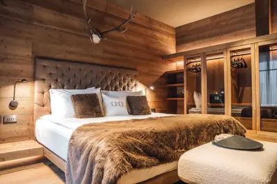 a bedroom with a large bed and wooden walls at Vila Muhr in Bohinj