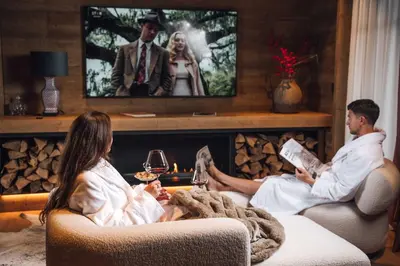 a man and woman sitting in a living room watching a movie at Vila Muhr in Bohinj