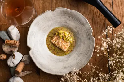 a plate with a bowl of soup on a wooden table at Vila Muhr in Bohinj