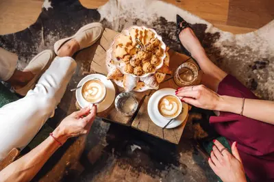 a group of people sitting around a table with coffee and food at Vila Muhr in Bohinj