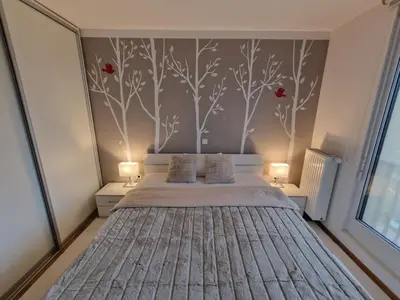 a bedroom with a bed with red flowers on the wall at Waldorf Apartment in Ljubljana
