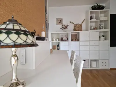 a white dining room with a table and a lamp at Waldorf Apartment in Ljubljana