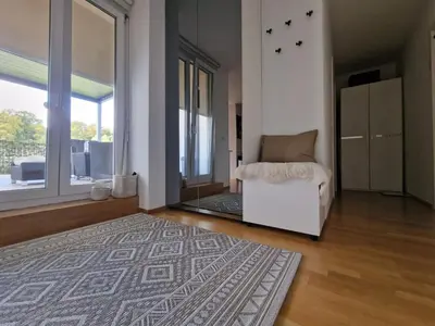 a living room with a white chair and a rug at Waldorf Apartment in Ljubljana