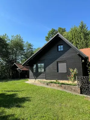 a black house with a grass yard in front of it at Chalet Neva in Loče pri Poljčanah