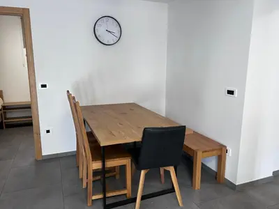 a wooden table with chairs and a clock on a wall at Apartment Angelina in Cerklje na Gorenjskem