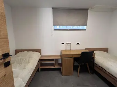 a room with two beds and a desk and a window at Apartment Angelina in Cerklje na Gorenjskem