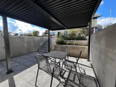 a table and chairs under awning on a patio at Apartment Angelina in Cerklje na Gorenjskem