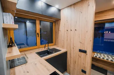 a kitchen with a sink and wooden walls and windows at Panorama Krvavec Ski-in, Ski-out in Cerklje na Gorenjskem