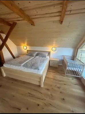 a bedroom with a bed in a wooden attic at Gorjuška Rozamunda in Bohinjska Bistrica