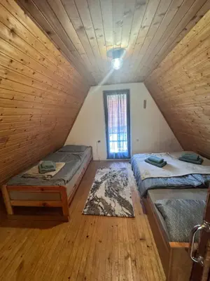 a attic room with two beds and a window at Chalet SS Pohorje in Pohorje