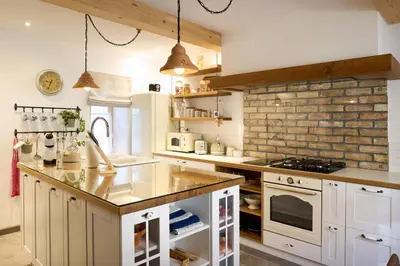 a kitchen with white cabinets and a brick wall at Pri Štefacovih - Authentic house in Grahovo