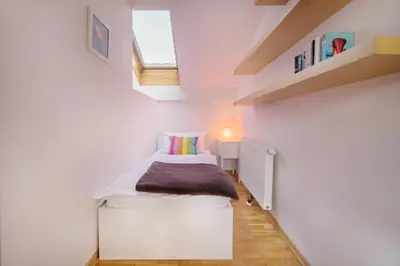 a small bedroom with a bed in a white room at City Central Ljubljana in Ljubljana