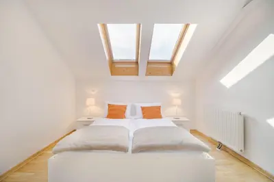 a white bedroom with two beds and two windows at City Central Ljubljana in Ljubljana