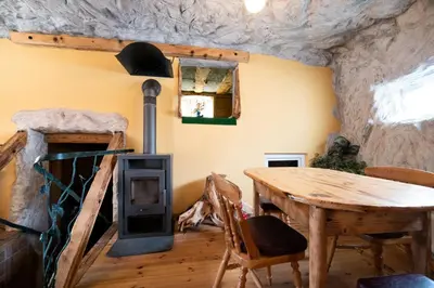 a room with a wooden table and a wood stove at Klub Zlata Ribica in Jesenice