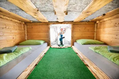 two beds in a wooden room with a green floor at Klub Zlata Ribica in Jesenice