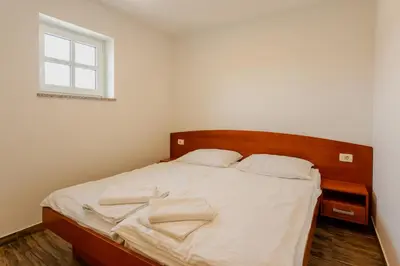 a bedroom with a bed with white sheets and a window at Sobe in apartmaji Triglav - Gostinstvo Tomex in Ilirska Bistrica