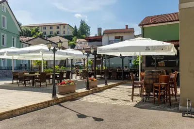 a patio with tables and chairs and umbrellas at Sobe in apartmaji Triglav - Gostinstvo Tomex in Ilirska Bistrica