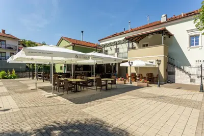 a patio with tables and white umbrellas in a courtyard at Sobe in apartmaji Triglav - Gostinstvo Tomex in Ilirska Bistrica