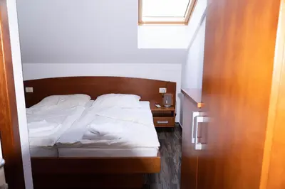 a bed with white sheets and pillows in a room at Sobe in apartmaji Triglav - Gostinstvo Tomex in Ilirska Bistrica