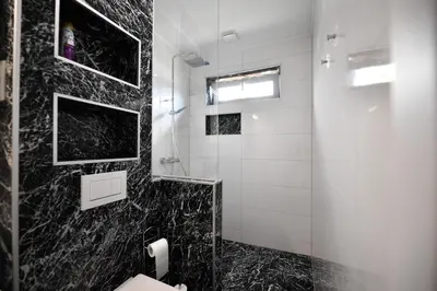 a black and white bathroom with a glass shower at CASA BOX PREMIUM free garage in Maribor