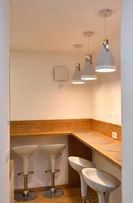 a kitchen with white stools and a counter with three lights at CASA BOX PREMIUM free garage in Maribor