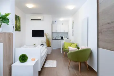 a living room with white furniture and green chairs at Central Castle Apartments in Ljubljana