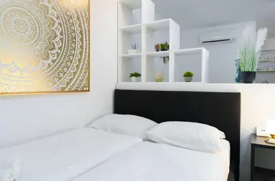 a white bedroom with a bed with white pillows at Central Castle Apartments in Ljubljana