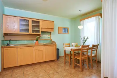 a kitchen with wooden cabinets and a table and chairs at Appartments Vrba, Terme Snovik in Laze v Tuhinju