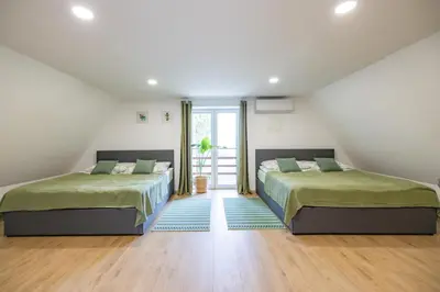two beds in a attic bedroom with a window at Hiška ViSa in Šoštanj