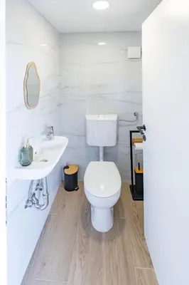 a white bathroom with a toilet and a sink at Hiška ViSa in Šoštanj
