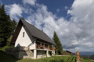 a white church with a black roof on a hill at Hiška ViSa in Šoštanj