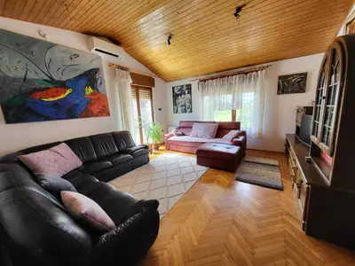 a living room with a black leather couch and a tv at Apartma ob meji in Šempeter pri Gorici