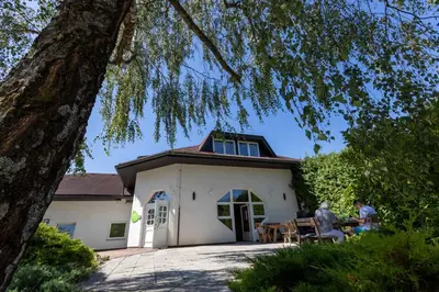 two people sitting at a table in front of a house at Brezov kot in Jesenice