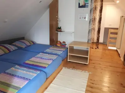 a bedroom with a blue bed and a table at Cottage Stela, family moutain hideout in Bohinj