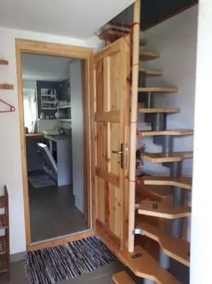 a door leading into a room with a spiral staircase at Cottage Stela, family moutain hideout in Bohinj