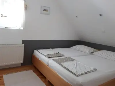 a bedroom with a bed with white sheets and a window at Cottage Stela, family moutain hideout in Bohinj