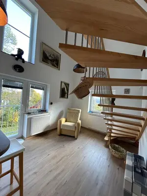 a living room with wooden stairs and a chair at Holiday house Gradišče in Škofljica