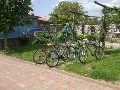 three bikes parked in a rack on the grass at Osterija Na Planinci in Divača