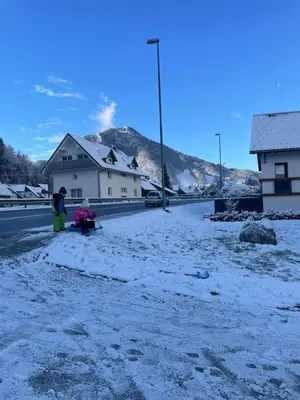 two people sitting on the side of a road in the snow at Apartment Zala with Sauna in Kranjska Gora