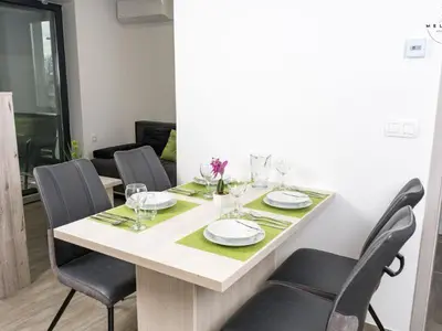 a table with chairs and plates and glasses on it at Meloria Apartments in Veržej