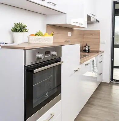 a kitchen with white cabinets and a black oven at Meloria Apartments in Veržej